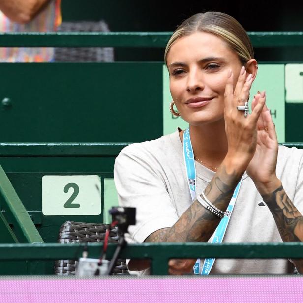 Sophia Thomalla mit Tattoos klatscht auf der Tribüne mit grünen Sitzen.