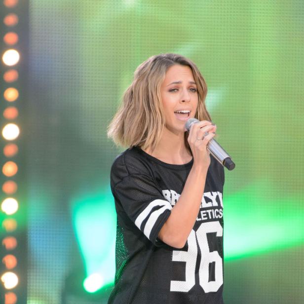 Vanessa Mai mit kurzem, blondem Haar singt in einem schwarzen Sporttrikot ins Mikrofon.