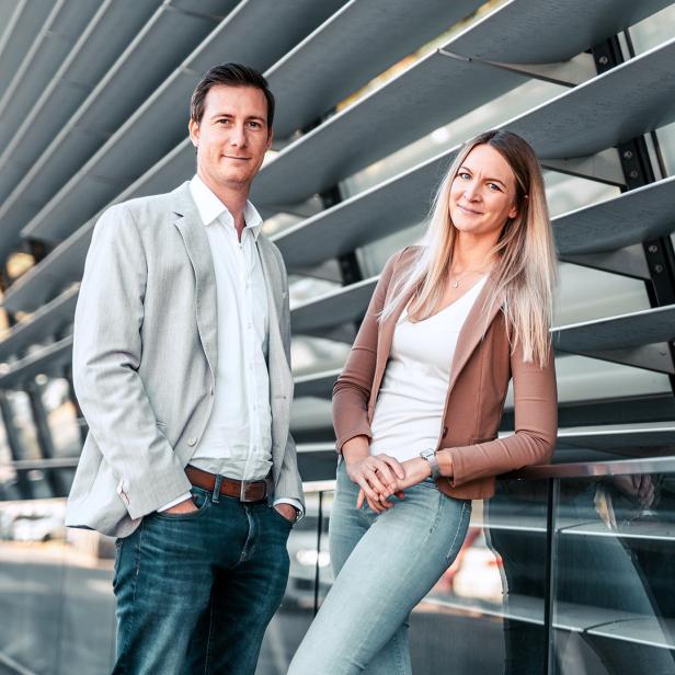 Ein Mann und eine Frau lehnen an einer Fassade