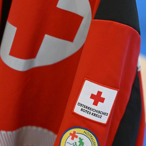 Rotes Kreuz Abzeichen und Notfalldienst Salzburg Aufnäher auf roter Jacke.