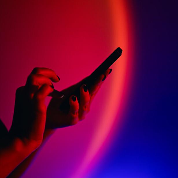 Person holding smartphone on vibrant neon background