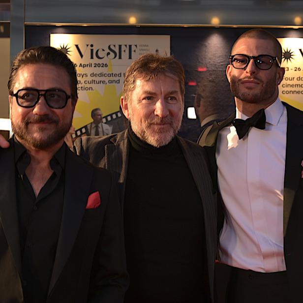 Drei Männer in Anzügen stehen nebeneinander