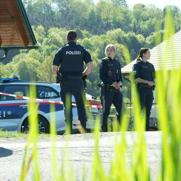 Drei Polizisten stehen vor einem Polizeiauto mit der Aufschrift "Polizei".