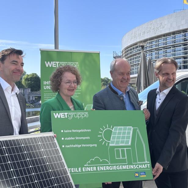 Vier Personen präsentieren ein Solarmodul und ein Schild der WET Gruppe vor einem Gebäude.