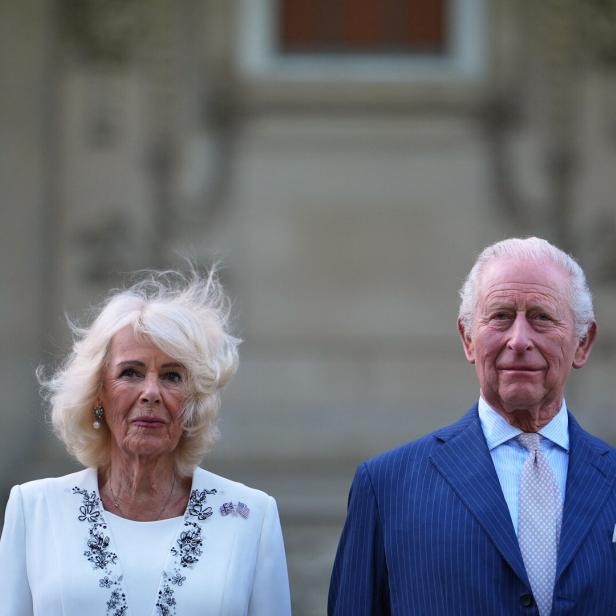 König Charles und Königin Camilla posieren vor einem Gebäude.