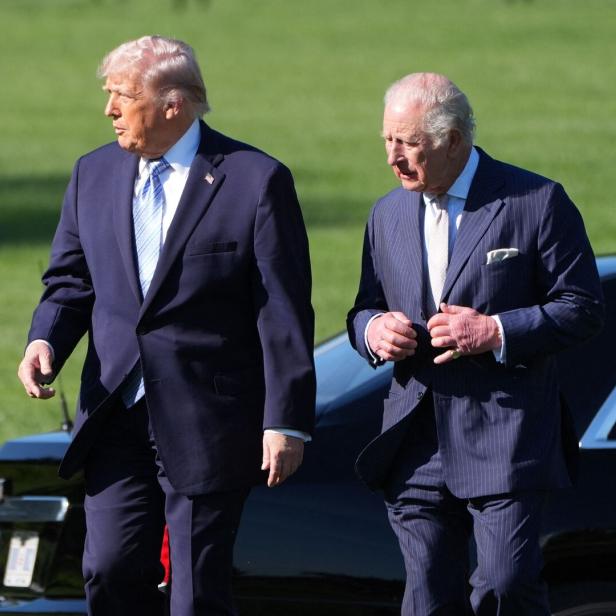 Donald Trump und König Charles III. gehen vor einem schwarzen Auto.