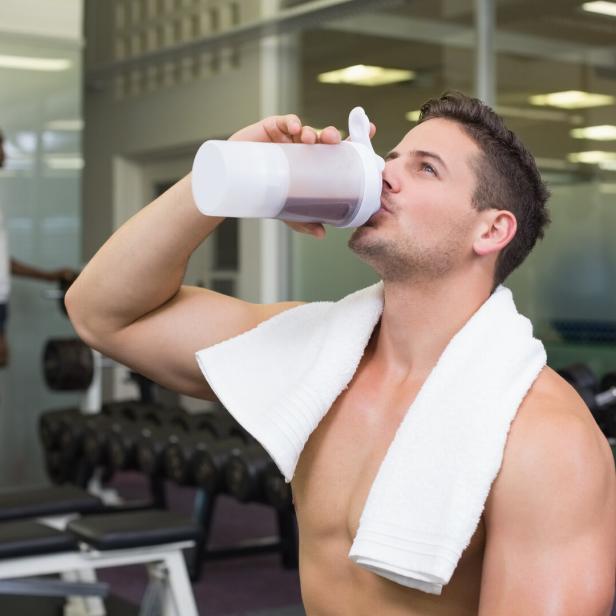 Ein Sportler trinkt ein Protein-Getränk in einem Fitnessstudio. 