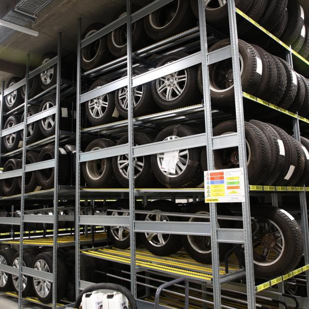 Mehrere Reihen Autoreifen mit Felgen sind ordentlich in einem Lagerregal gestapelt.