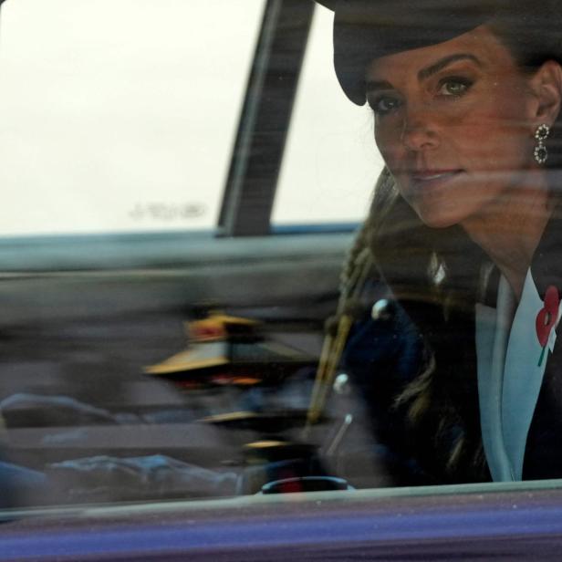 Prinzessin Kate, mit Hut und Mohnblume, blickt aus dem Autofenster.