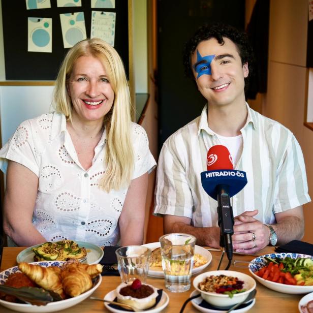 Claudia Stöckl und Cosmó sitzen am gedeckten Frühstückstisch