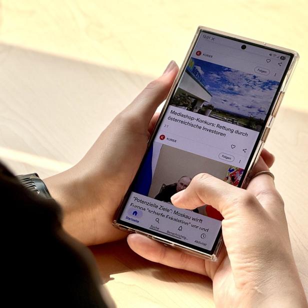Eine Person hält ein Android-Handy und scrollt durch  Google.