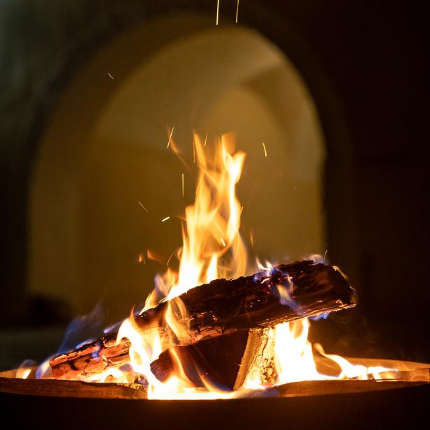 Loderndes Feuer in einer Feuerschale vor einem Kirchengewölbe, stimmungsvolle Atmosphäre während der Langen Nacht der Kirchen in Wien.