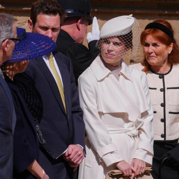 Mehrere Personen, darunter Sarah Ferguson und Prinzessin Eugenie mit Hut und Schleier, stehen beisammen.