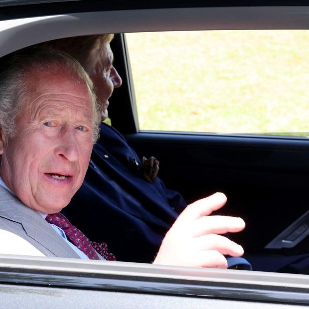 König Charles III. schaut aus dem Autofenster und gestikuliert mit der Hand.