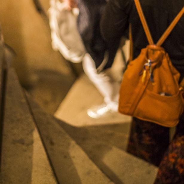 Besucher steigen eine enge Steintreppe in den historischen Keller einer Wiener Kirche hinab, wie es bei der Langen Nacht der Kirchen für Führungen und Escape-Spiele angeboten wird.