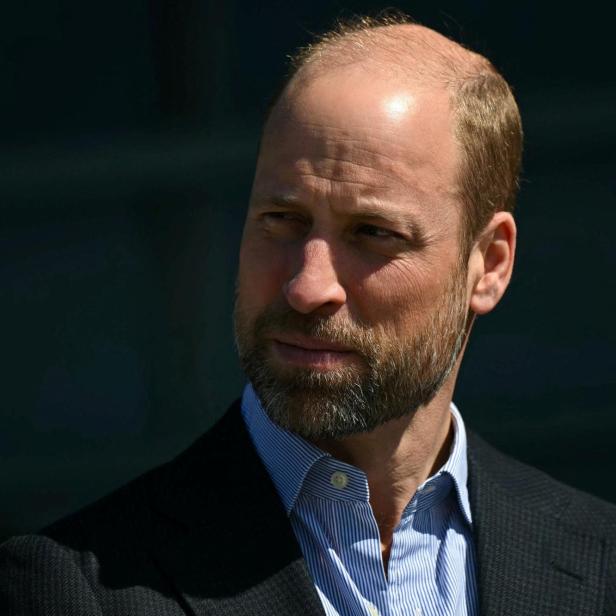 Prinz William mit Bart und blau gestreiftem Hemd blickt zur Seite.