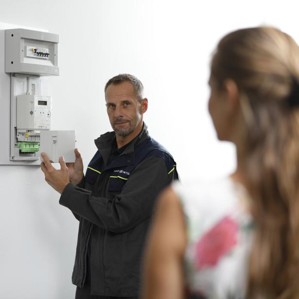 Techniker eines Stromnetzbetreibers zeigt Kundin ihren neuen Smart Meter.