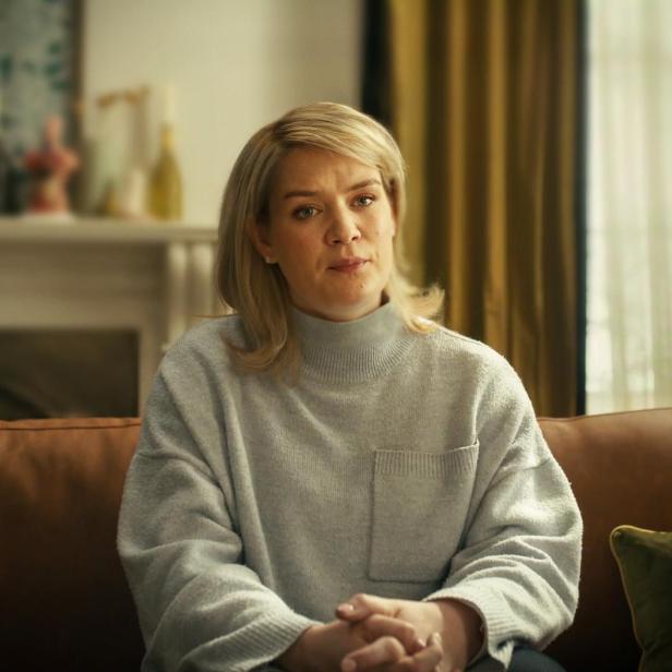 Blonde Frau sitzt auf einem Sofa 
