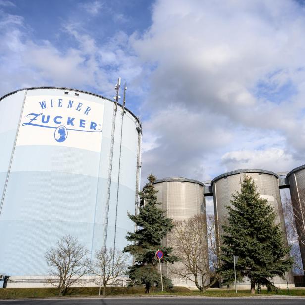 Mehrere Silos von "Wiener Zucker" stehen unter einem bewölkten Himmel.