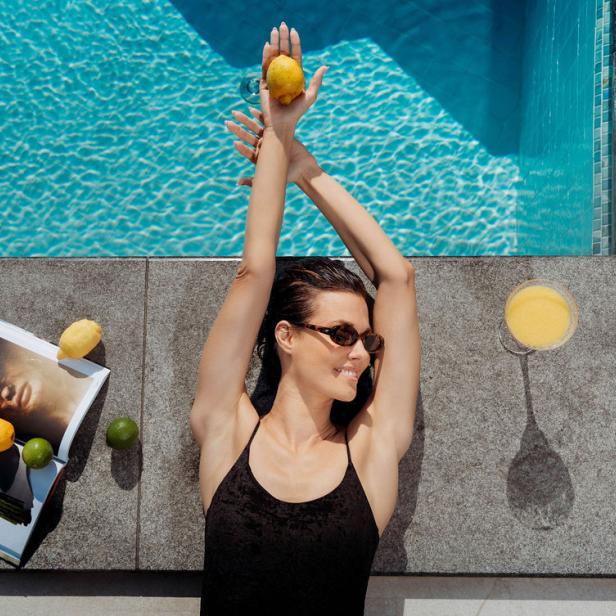 Eine Frau liegt lächelnd am Pool 