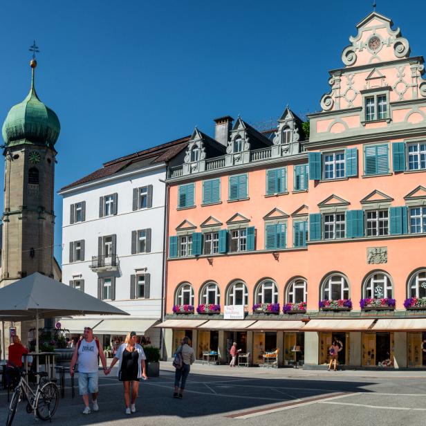 People walking around the rathaus square near chapel of saint george and hilarius in the austrian city bregenz.