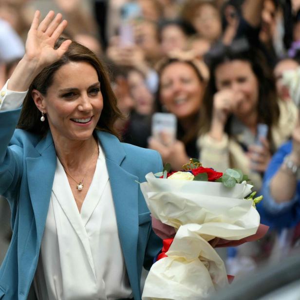 Prinzessin Kate winkt lächelnd in der Menge, einen Blumenstrauß haltend.