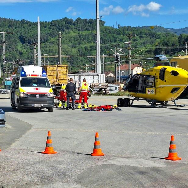 Ein gelber Rettungshubschrauber, ein Rettungswagen und ein Polizeiauto stehen bei einem medizinischen Notfall bereit.