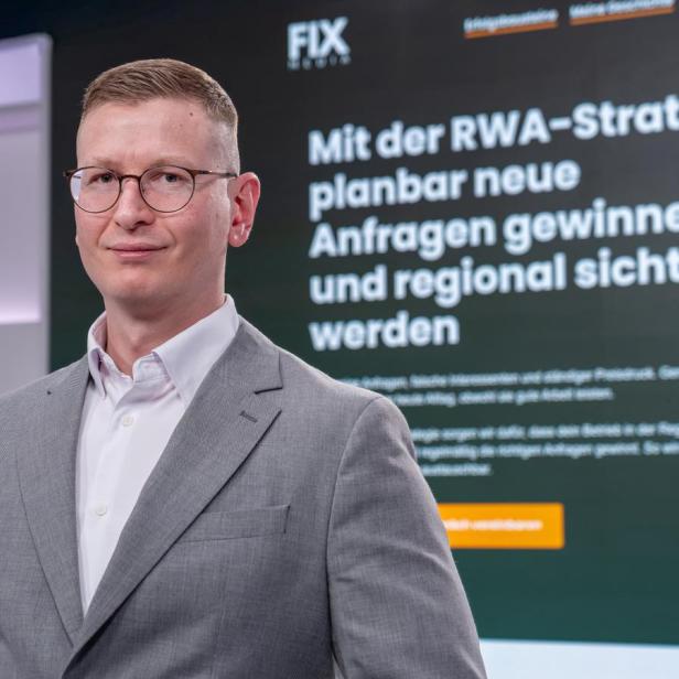 Geschäftsmann im grauen Anzug vor digitaler Präsentationsfläche.
