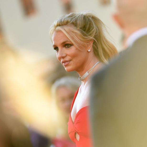 Britney Spears mit hochgesteckten blonden Haaren und rotem Kleid auf einem Event.