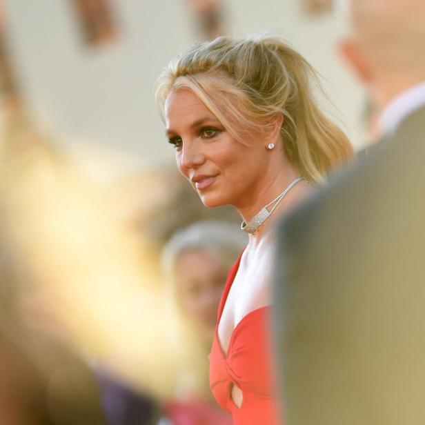 Britney Spears mit hochgesteckten blonden Haaren und rotem Kleid auf einem Event.