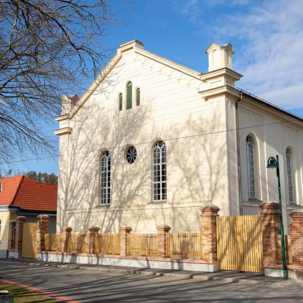 Ehemalige Synagoge Kobersdorf mit hellem Mauerwerk und roten Dachziegeln bei Sonnenschein.