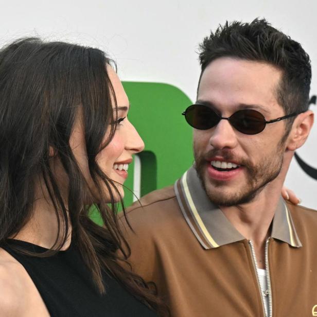 Pete Davidson mit Sonnenbrille und Elsie Hewitt schauen sich vor einem "Prime"-Logo an.