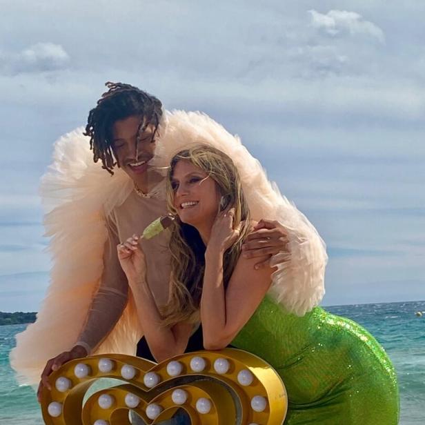 Heidi Klum und ihr Sohn Henry posieren am Strand mit einem Eis und einem Herz aus Lichtern.