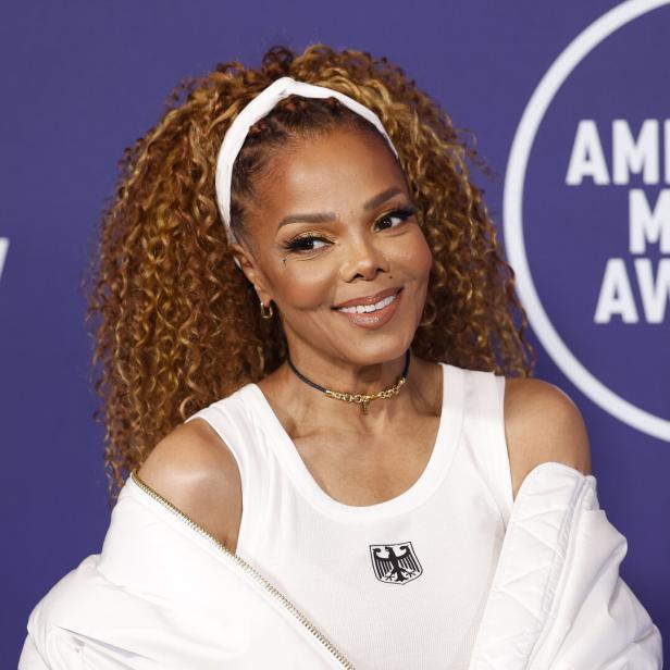 Janet Jackson lächelt vor einem Hintergrund der American Music Awards.