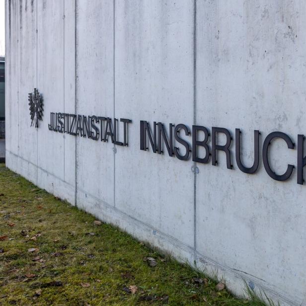Die Aufschrift "Justizanstalt Innsbruck" ist an einer grauen Betonmauer angebracht.