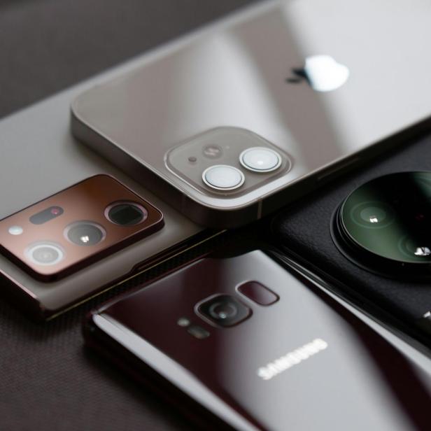 Nahaufnahme von vier Smartphones unterschiedlicher Marken mit Fokus auf die Kameramodule auf der Rückseite.