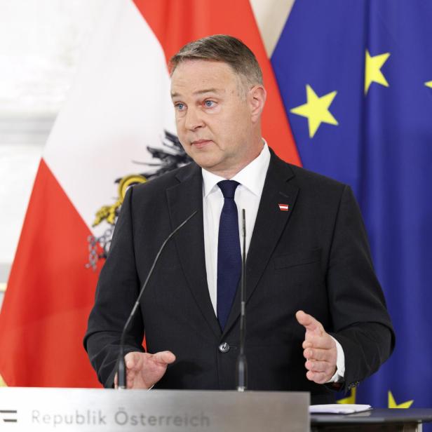 Ein Mann im Anzug spricht an einem Rednerpult vor österreichischer und EU-Flagge.