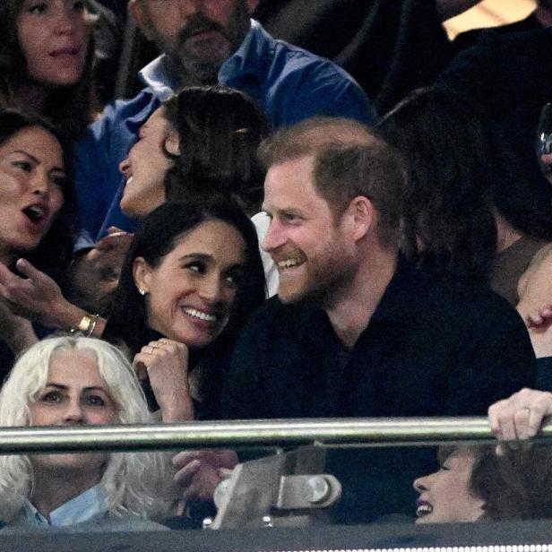 Prinz Harry und Meghan, die Herzogin von Sussex, lächeln inmitten einer Menschenmenge.