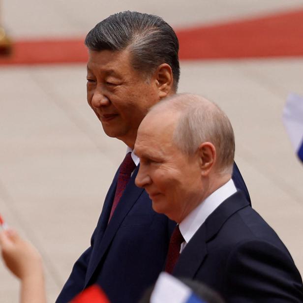 Xi Jinping und Wladimir Putin gehen an winkenden Flaggen vorbei.