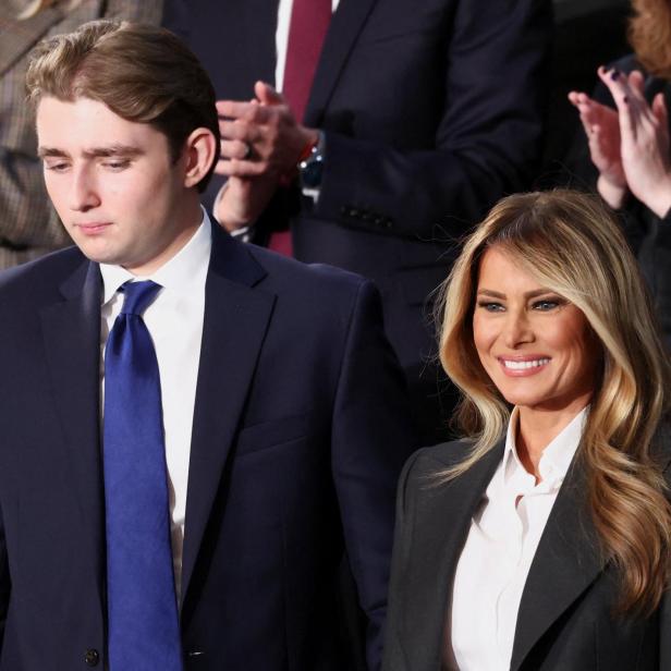 Melania Trump lächelt neben ihrem Sohn Barron mit dunklem Anzug und blauer Krawatte.