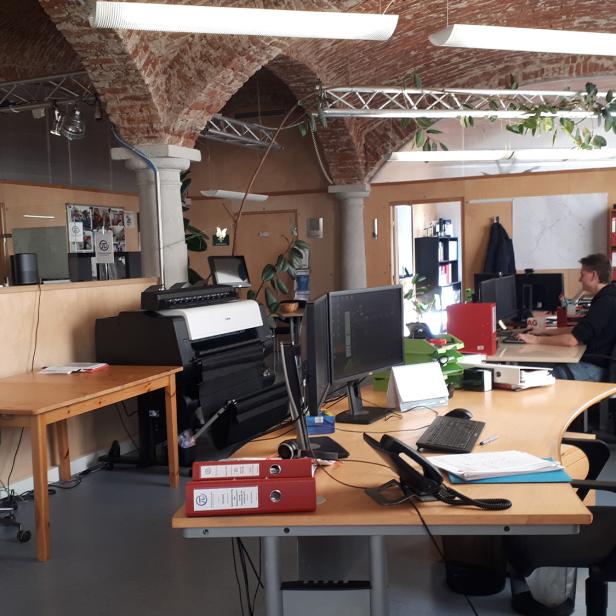 Ein Büro mit mehreren Arbeitsplätzen unter gemauerten Deckenbögen und moderner Büroausstattung.