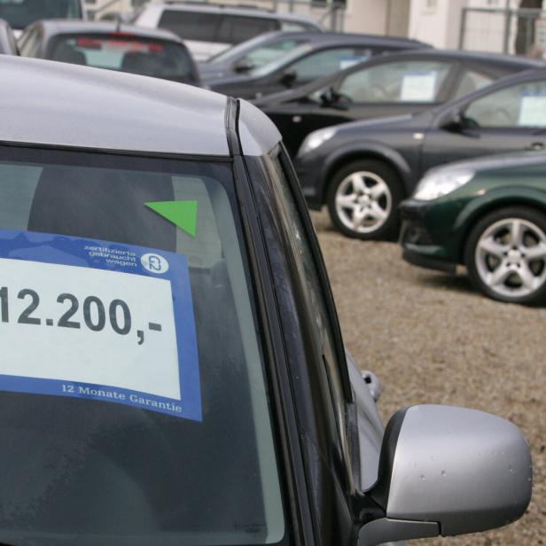 Mehrere Gebrauchtwagen stehen auf einem Parkplatz, eines davon ist für 12.200 Euro mit 12 Monaten Garantie ausgezeichnet.