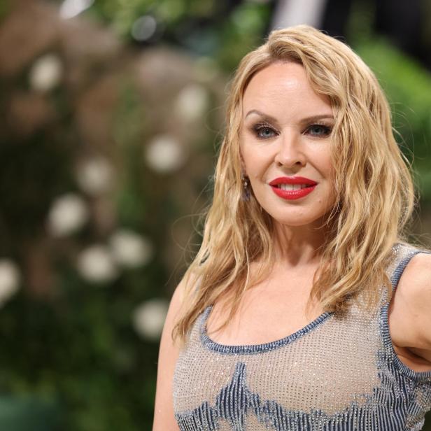 Kylie Minogue lächelt mit rotem Lippenstift und blonden, gewellten Haaren.