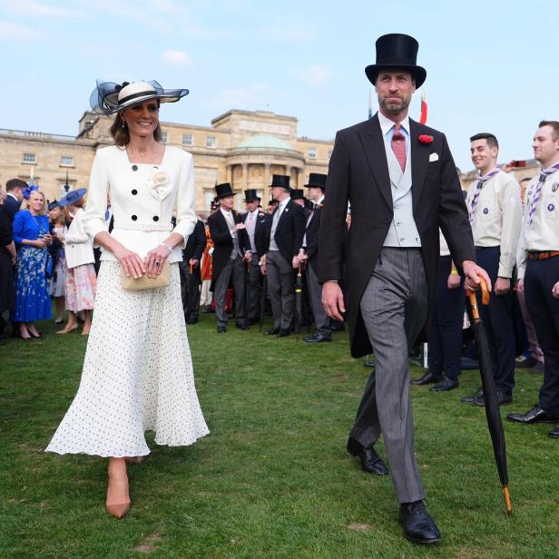 Kate und William gehen über einen Rasen, umgeben von Zuschauern.