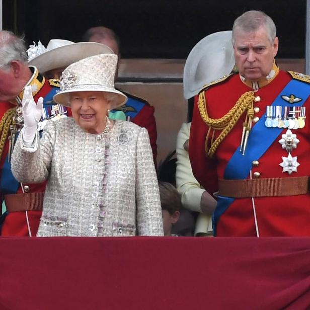Königin Elisabeth II. winkt, flankiert von Prinz Charles und Prinz Andrew in Uniformen.