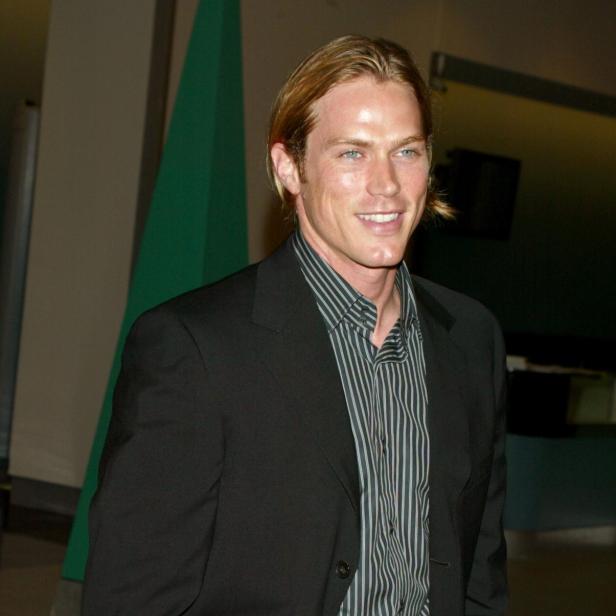 Jason Lewis mit halblangen Haaren, gestreiftem Hemd und Anzug.