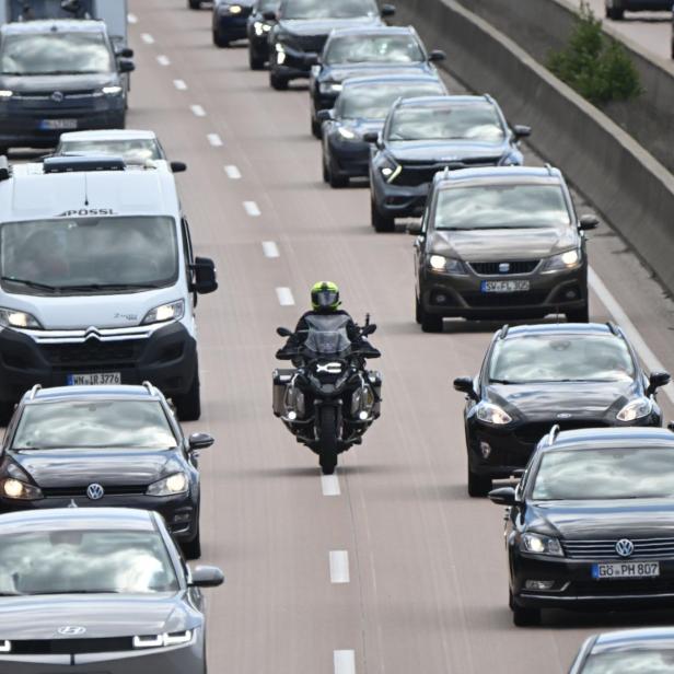 Motorradfahrer zwischen dichtem Auto- und Lieferwagenverkehr auf mehrspuriger Autobahn.