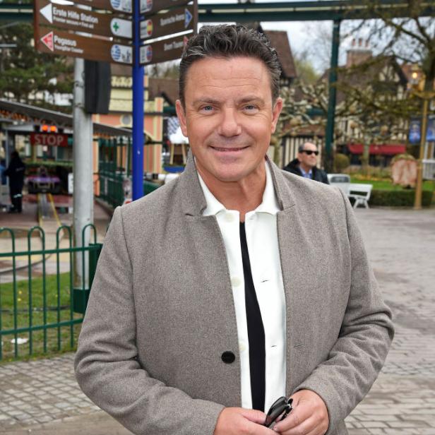 Stefan Mross steht draußen in Freizeitkleidung und blickt lächelnd in die Kamera.