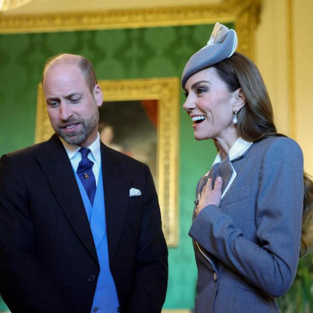 Prinz William und Prinzessin Kate in formeller Kleidung, sie lächelt mit der Hand auf der Brust.