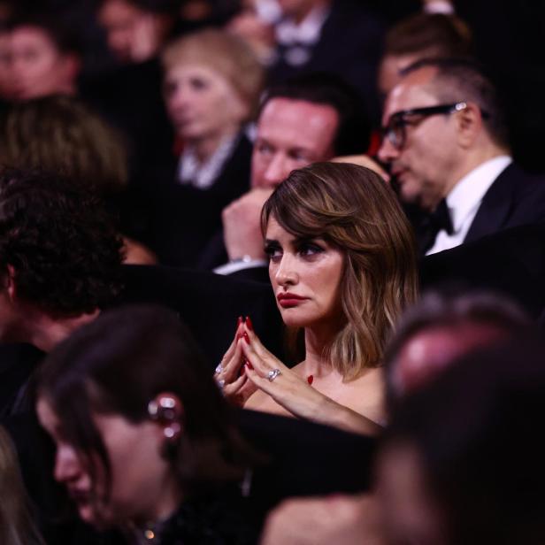 Penélope Cruz sitzt im Publikum, die Hände gefaltet, umgeben von anderen Gästen.